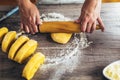 Woman rolled out pasta dough on the table with the rolling pin