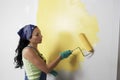Woman With Roller Applying Yellow Paint On A Wall