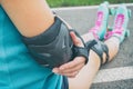 Woman rollerskater putting on elbow protector pads on her hand