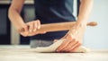 Woman rolling dough on wooden table with wooden rolling pin Royalty Free Stock Photo