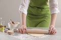 Woman rolling fresh dough at light grey marble table, closeup. Cooking grissini