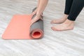 Woman rolling her mat after a yoga class on a wooden floor at home. Girl doing yoga exercises Royalty Free Stock Photo