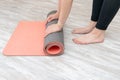 Woman rolling her mat for yoga exercises on a wooden floor at living room at home. Royalty Free Stock Photo