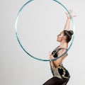 Woman rotates hula hoop in hands on grey background. Royalty Free Stock Photo