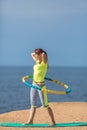 Woman rotates hula hoop on summer beach Royalty Free Stock Photo