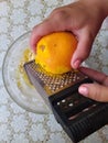 Woman rub citron from orange with grater in bowl Royalty Free Stock Photo