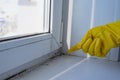 Hand in rubber protective glove pointing to the mold in the window corner. Copy space. Selective focus.