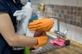 Woman in rubber gloves holding plastic bottles of washing liquid on the kitchen Royalty Free Stock Photo