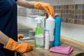 Woman in rubber gloves holding plastic bottles of washing liquid on the kitchen Royalty Free Stock Photo