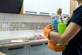 Woman in rubber gloves holding plastic bottles of washing liquid on the kitchen Royalty Free Stock Photo