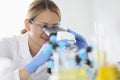 Woman in rubber gloves and protective chemical glasses looks through microscope in laboratory portrait Royalty Free Stock Photo