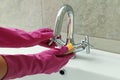 Woman in rubber pink glove cleaning sink