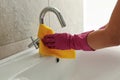 Woman in rubber pink glove cleaning sink