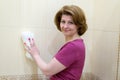 Woman rubs the tile in bathroom