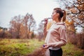 Woman runner drinks water in autumn forest