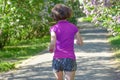 Woman runner jogging in spring park with lilac blossom, morning run outdoors, fitness and running Royalty Free Stock Photo