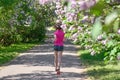 Woman runner jogging in spring park with lilac blossom, morning run outdoors, fitness and running Royalty Free Stock Photo