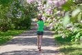 Woman runner jogging in spring park with lilac blossom, morning run outdoors, fitness and running Royalty Free Stock Photo