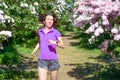 Woman runner jogging in spring park with lilac blossom, morning run outdoors, fitness and running Royalty Free Stock Photo