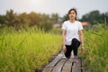 Woman runner stretching legs before run on wooden path in field Royalty Free Stock Photo