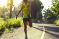 Woman runner stretching legs before running at morning tropical forest trail Royalty Free Stock Photo