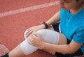 Woman runner suffering from pain in legs be injured,Hand touching her knee after jogging on track running Royalty Free Stock Photo