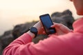 Woman Runner Syncing Fitness Data between the Smartwatch and Smartphone after Workout. Sports and Technology Concept Royalty Free Stock Photo