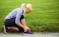 Woman runner tying running shoes. Blonde Girl over Grass Royalty Free Stock Photo