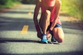 Woman runner tying shoelace on morning tropical forest trail