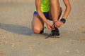 Woman runner tying shoelace before run on sunset beach Royalty Free Stock Photo