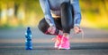 Woman runner tying shoelaces before jogging in autumn tree alley park. Sports female autumn outfit leggings and thermal underwear Royalty Free Stock Photo