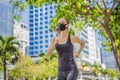 Woman runner wearing medical mask. Running in the city against the backdrop of the city. Coronavirus pandemic Covid-19