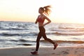 Woman running alone at beautiful dusk on the beach