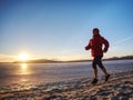 Woman running along shore of a frozen lake in winter spring Royalty Free Stock Photo