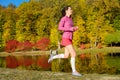 Woman running in autumn park, beautiful girl runner jogging