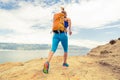 Woman running with backpack on rocky trail at seaside Royalty Free Stock Photo