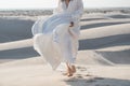 Woman running barefoot in desert in beautiful flowing bridal white dress