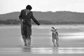 Woman running on deserted beautiful beach with pet dog