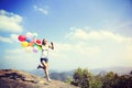 Woman running on mountain peak rock with colored balloons