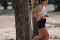 Woman running in park on a sunny day. Focus on tree.