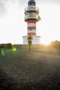 Woman running past a lighthouse as the sun sets