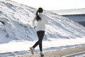 Woman running past hill in winter, back view. Outdoors sports exercises