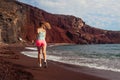 Woman running on Red beach on Santorini island. Female runner jogging during outdoor workout on seashore Royalty Free Stock Photo