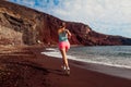 Woman running on Red beach on Santorini island. Female runner jogging during outdoor workout on seaside Royalty Free Stock Photo