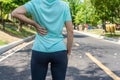 Woman on running road in the park having a back pain