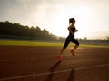 Woman running during sunny morning on stadium track Royalty Free Stock Photo