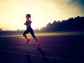 Woman running during sunny morning on stadium track Royalty Free Stock Photo