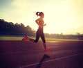 Woman running during sunny morning on stadium track Royalty Free Stock Photo
