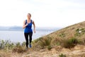 Woman running up hill with sea in background Royalty Free Stock Photo