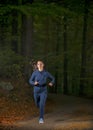 Woman running in wooded forest area, training and exercising for trail run marathon endurance Royalty Free Stock Photo